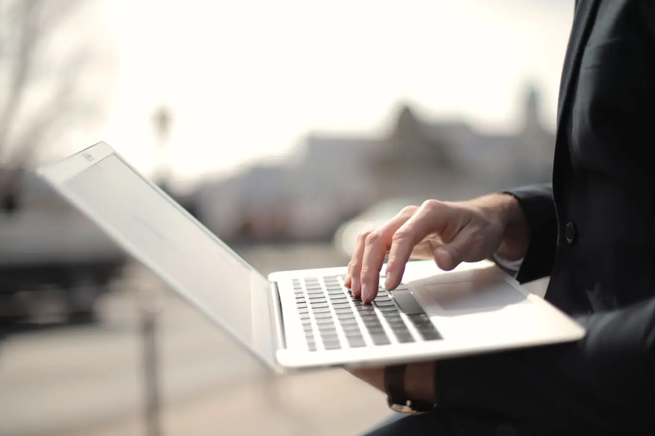 A business professional typing on a laptop in an outdoor setting, symbolizing remote work. - Why Tomorrow's Tech Is Today's Business Imperative