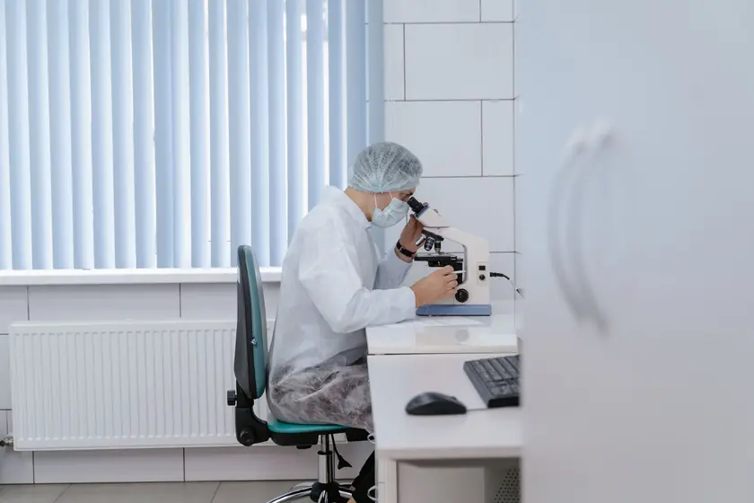 ラボで顕微鏡を使用する研究者、バイオテクノロジーの応用を示しています。