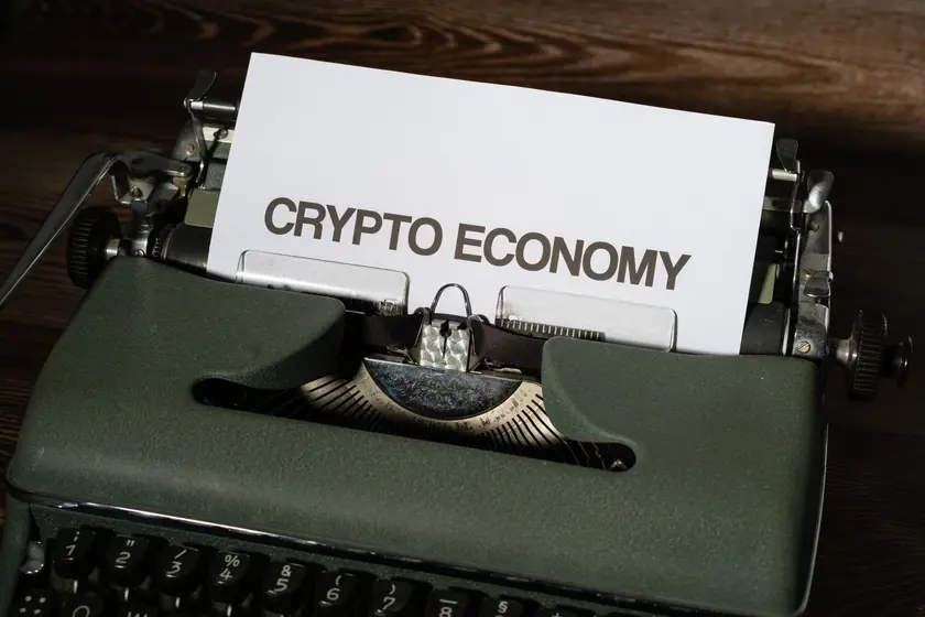 Primer plano de una máquina de escribir vintage con papel que dice 'Crypto Economy', simbolizando conceptos modernos con tecnología retro.